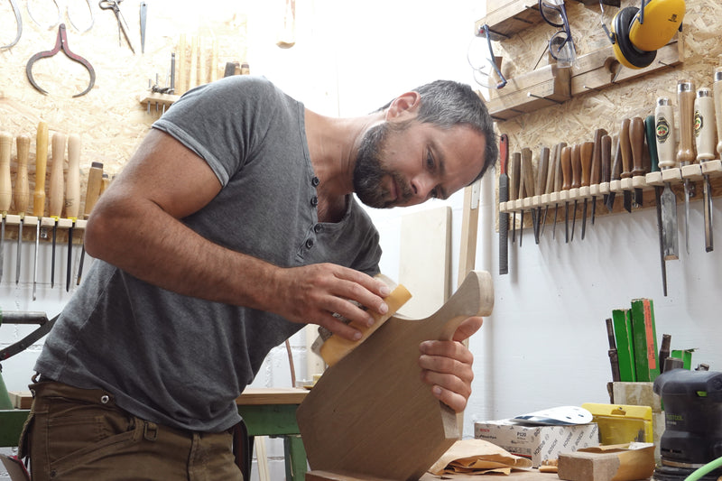 Der Inhaber der Manufaktur Nissen bei der Schleifarbeit eines Holzbrettes in der Werkstatt
