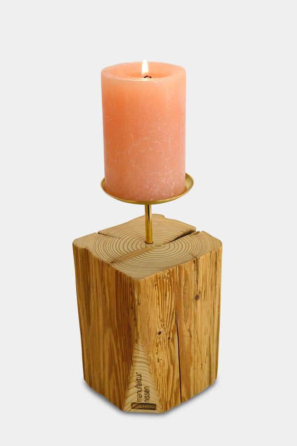 handgefertigter Kerzenständer der Manufaktur Nissen aus unbehandeltem Altholz mit Tropfschale aus Messing und brennender lachsfarbenen Stumpenkerze
