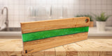Hochwertiges handgefertigtes Servierbrett, Schneidebrett oder Küchenbrett  der Grösse L der Manufaktur Nissen aus schweizer Eichenholz mit Veredelung aus grünem biobasiertem Epoxidharz im River Flow Design  in der Schrägansicht in Küche